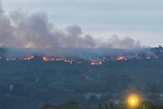 Line of fire and smoke along the ridge of Drummau Mountain at dusk, seen above rooftops