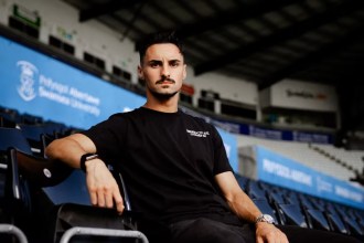 Stephen Eustáquio in a black Swansea City AFC t-shirt sitting in the stands at the Swansea.com Stadium