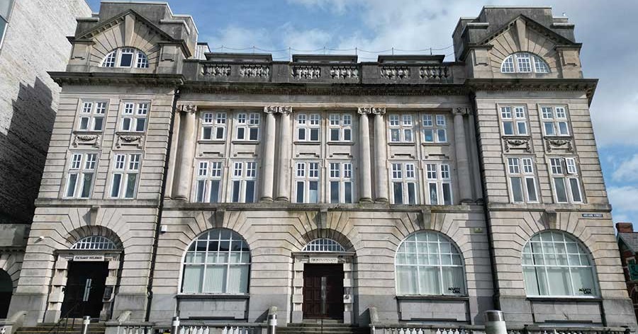 The stone front elevation of the Grade II listed Exchange Buildings on Adelaide Street in Swansea