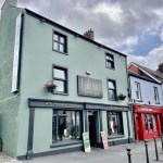 The Falcon Hotel on Lammas Street, Carmarthen, a three-storey sage green building with bilingual signage