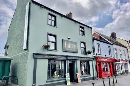 The Falcon Hotel on Lammas Street, Carmarthen, a three-storey sage green building with bilingual signage