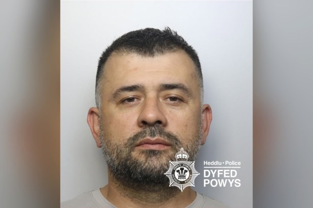 Custody image of Florin Kasmi against a grey background with the Dyfed-Powys Police watermark
