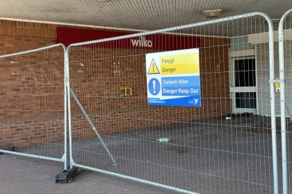 The former Wilko store entrance at Friars Park, Carmarthen, behind metal fencing with a bilingual Danger Keep Out sign