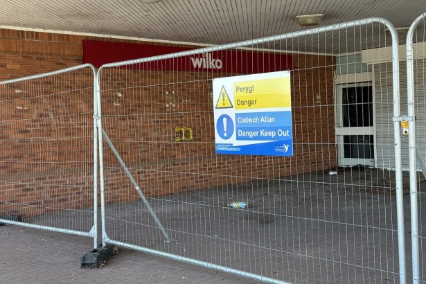 The former Wilko store entrance at Friars Park, Carmarthen, behind metal fencing with a bilingual Danger Keep Out sign