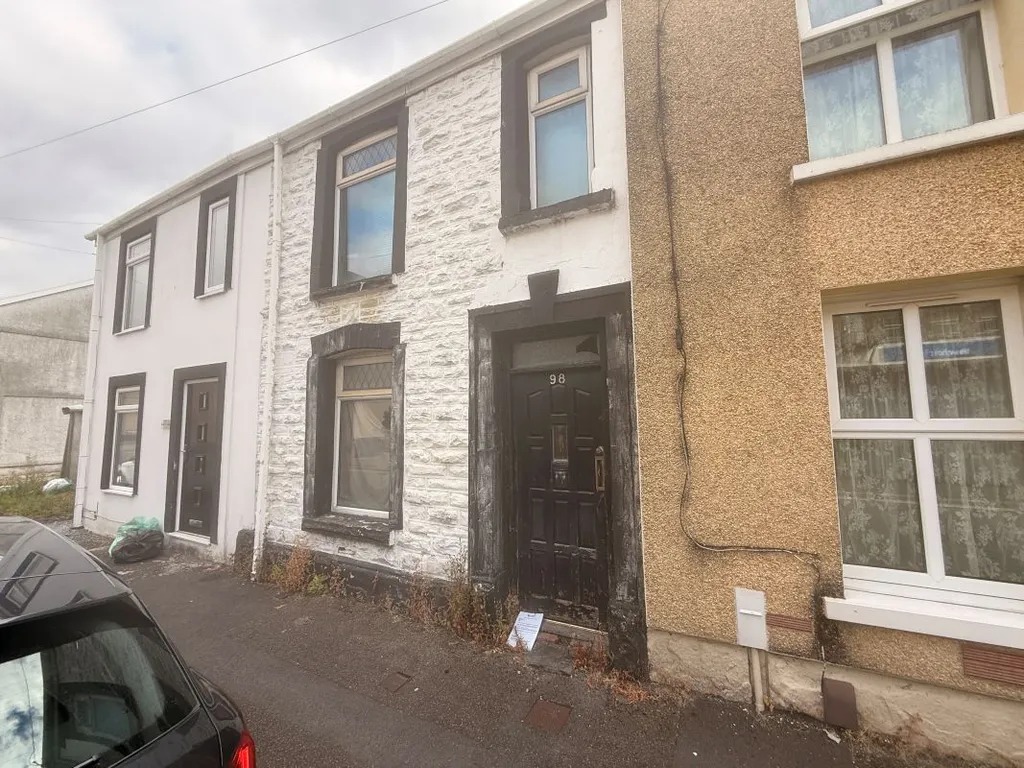 A terraced house on Glantawe Street with a black front door and render coming away from the frontage