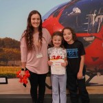 Emma Kinnear with her daughter Gracie holding a Child of Wales certificate and her son Chester at the Wales Air Ambulance base