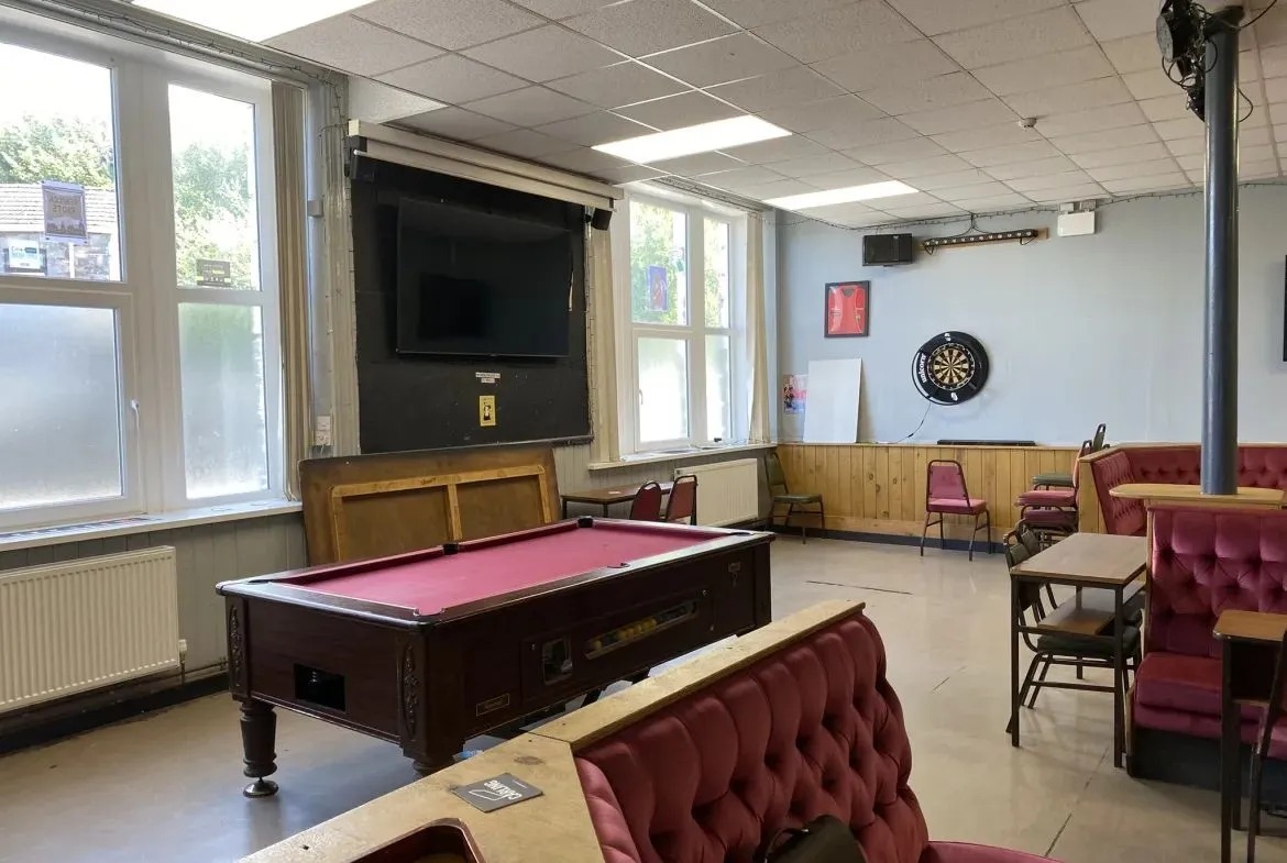 A pool table, dartboard and upholstered banquettes in the games room of the Great Mountain club