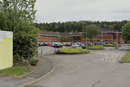 The entrance to HM Land Registry's Swansea office, with a bilingual sign beside the access road and the red-brick office building behind a car park