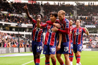 Swansea City players celebrating a goal in their red and blue away kit at Pride Park
