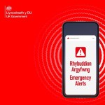 The UK Government Emergency Alerts graphic showing a phone displaying Rhybuddion Argyfwng and Emergency Alerts on a red background
