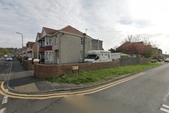 A Google Street View image of the grass verge on the corner of Iscoed Road and Maes y Coed in Llanelli, with the Iscoed street sign