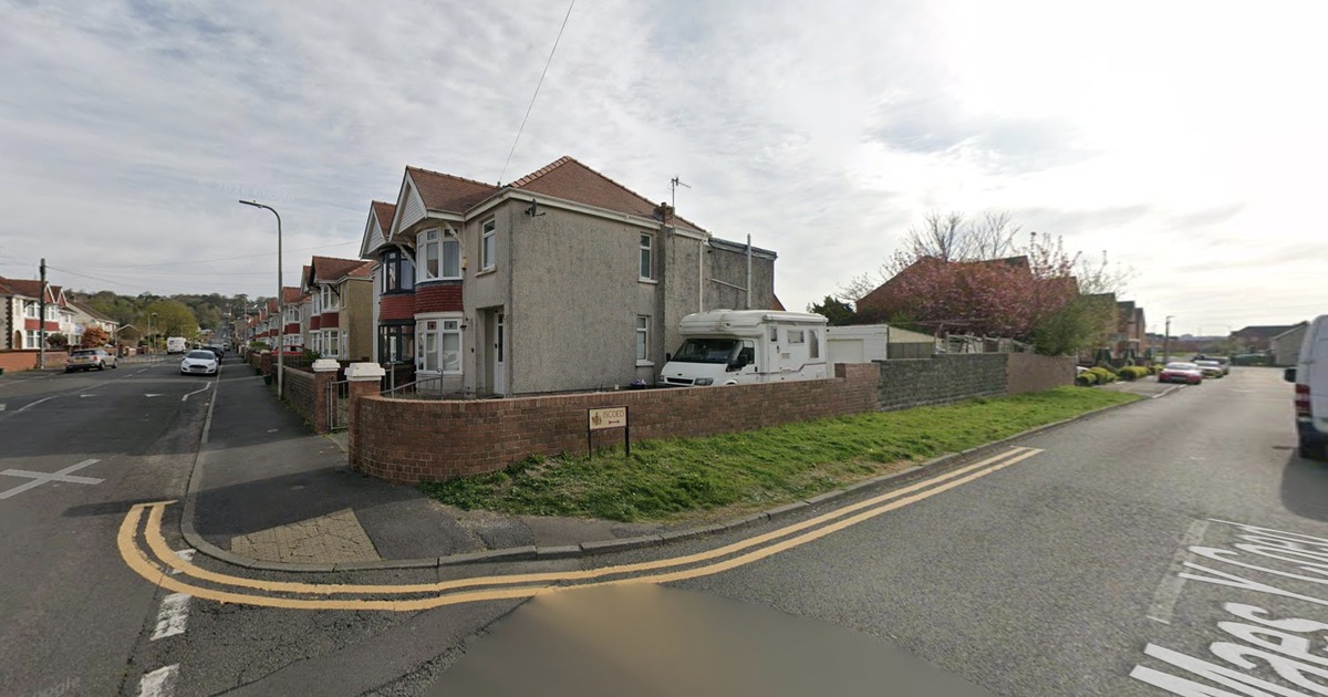 A Google Street View image of the grass verge on the corner of Iscoed Road and Maes y Coed in Llanelli, with the Iscoed street sign
