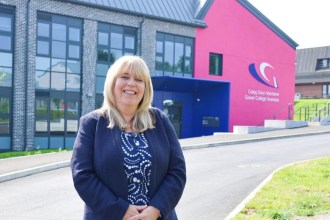 Kelly Fountain standing in front of the redeveloped Gorseinon campus entrance with the college's pink signage behind her