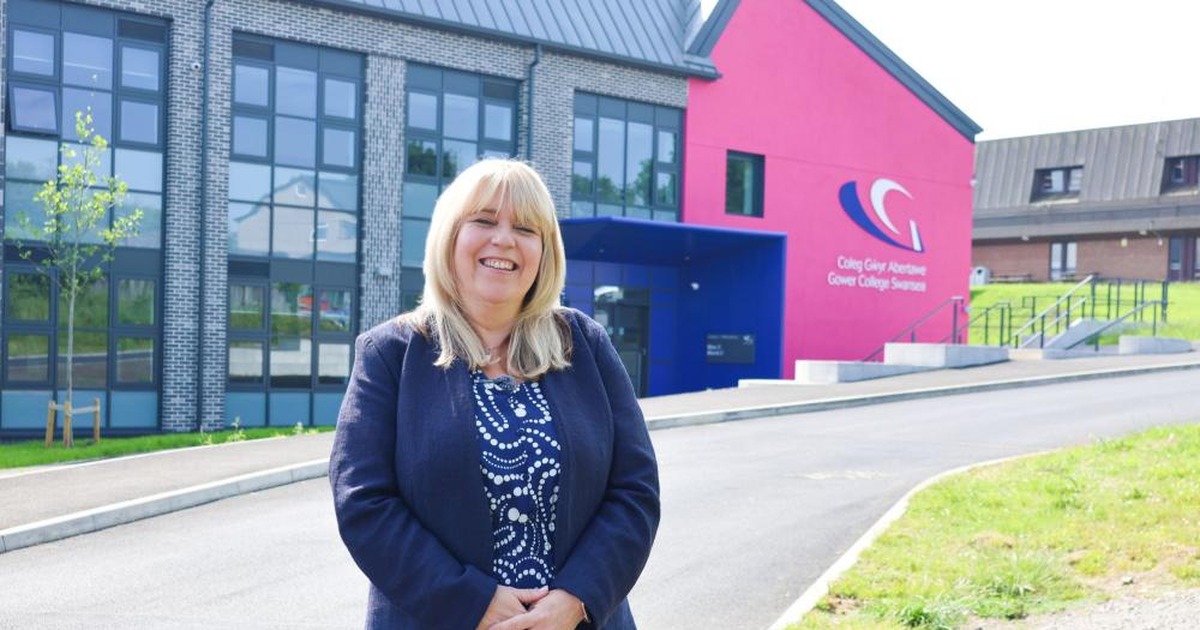 Kelly Fountain standing in front of the redeveloped Gorseinon campus entrance with the college's pink signage behind her