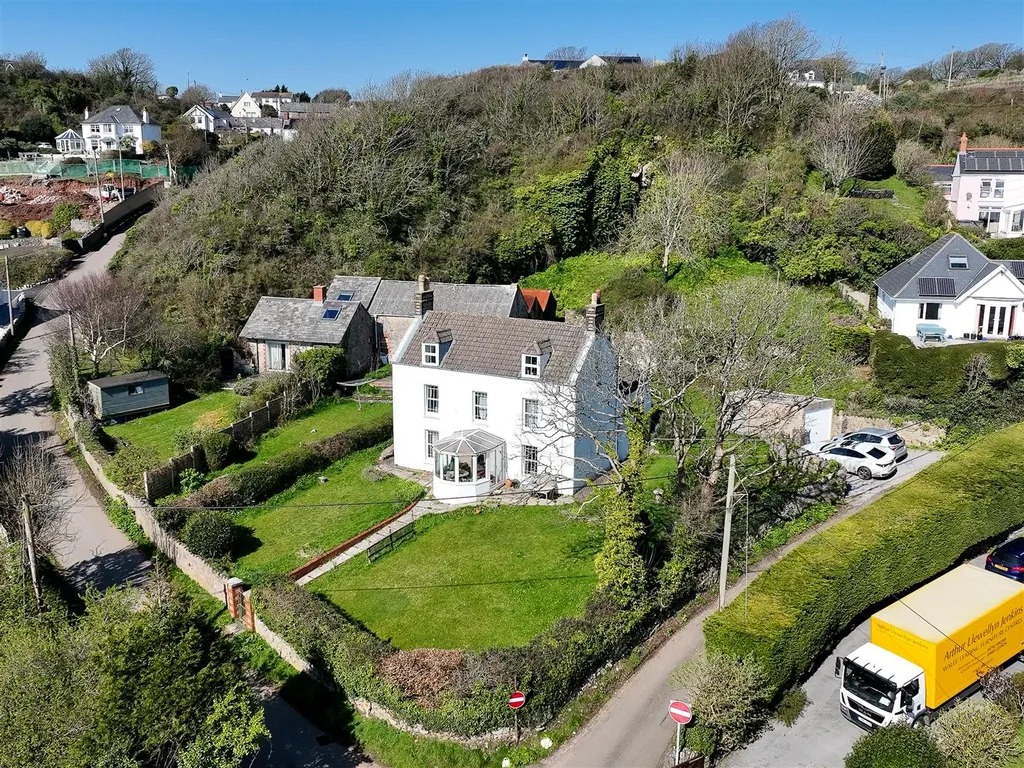 Aerial view of a white detached house in Horton with lawns, outbuildings and the village around it
