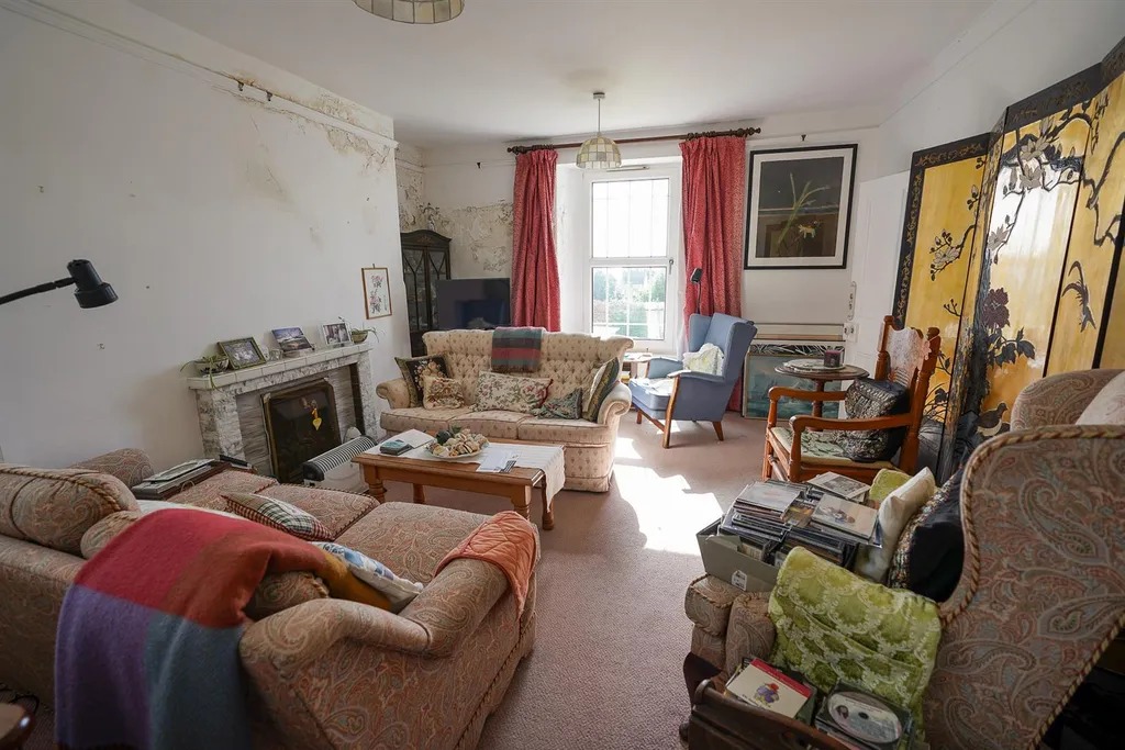 A sitting room with sofas, a fireplace and plaster missing from the wall beside it