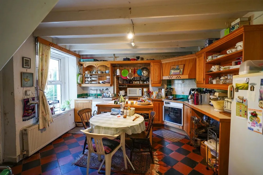 A pine kitchen with a round table and red and black quarry tiled floor