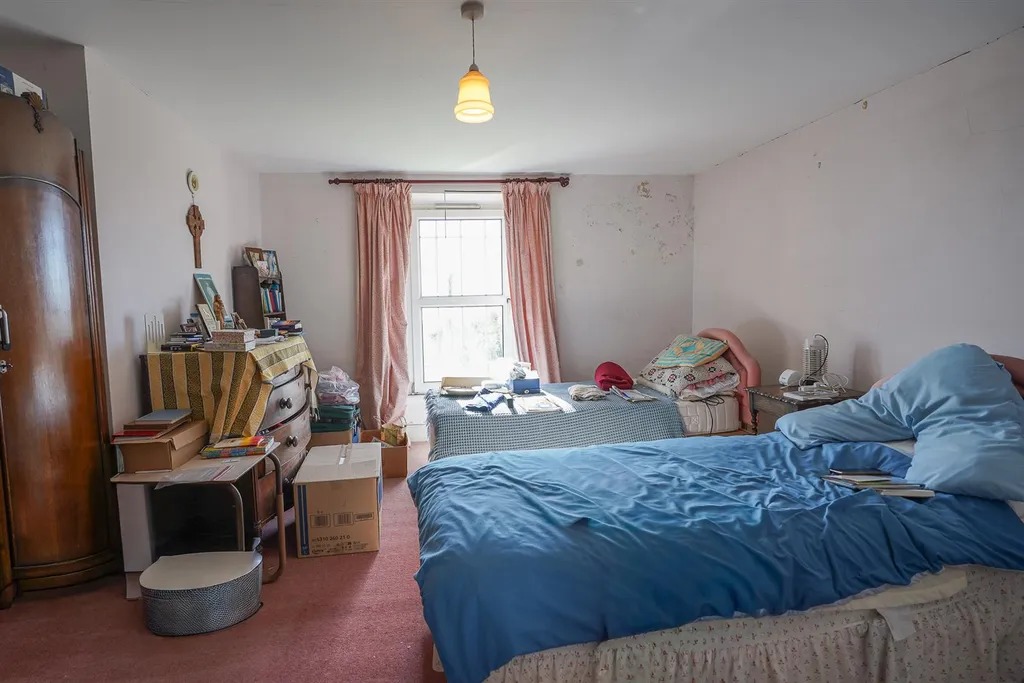 A bedroom with two beds, a wardrobe and marks across the wall above