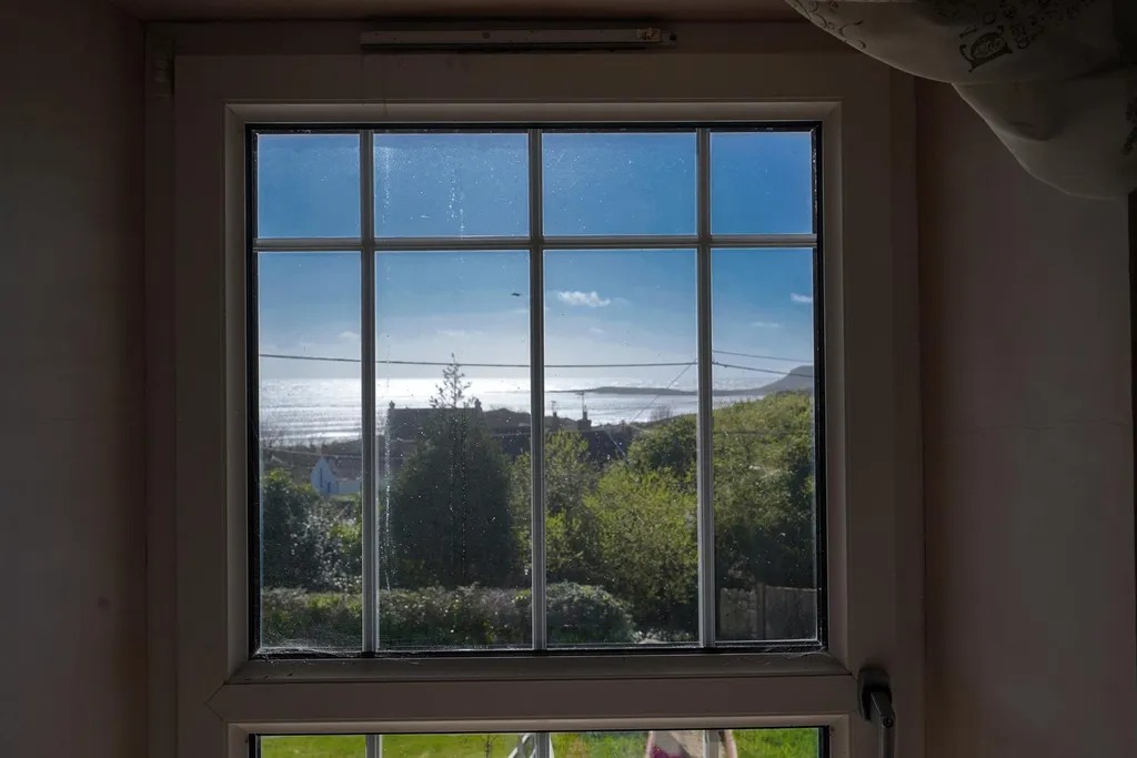 The sea at Port Eynon Bay seen through a small paned bedroom window
