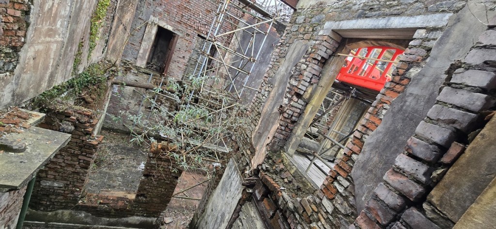 The derelict interior of the Laboratory Building with crumbling brickwork, scaffolding and vegetation growing through the walls