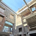 Steel beams and timber joists span the interior of the roofless stone Laboratory Building, with scaffolding and blue sky above