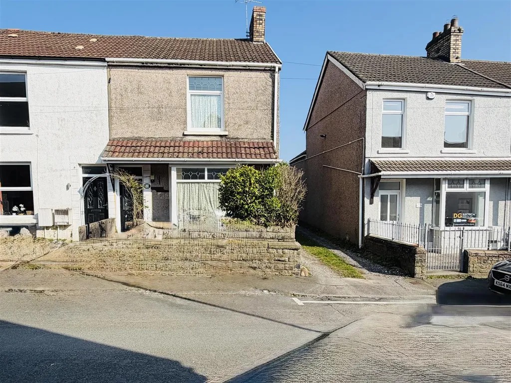 A rendered end of terrace house on Llewelyn Street with an overgrown frontage