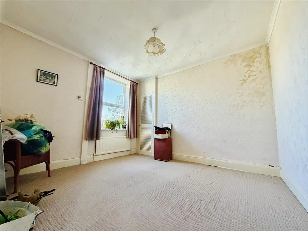 A largely empty bedroom with staining visible across one wall