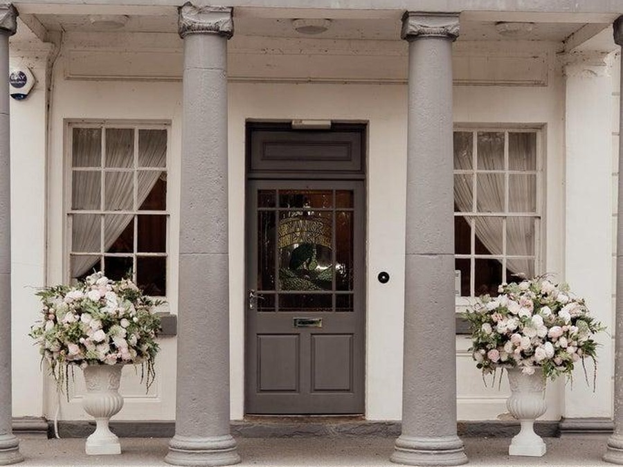 The columned entrance porch at Manor Park Country House, Clydach, with flowers in stone urns