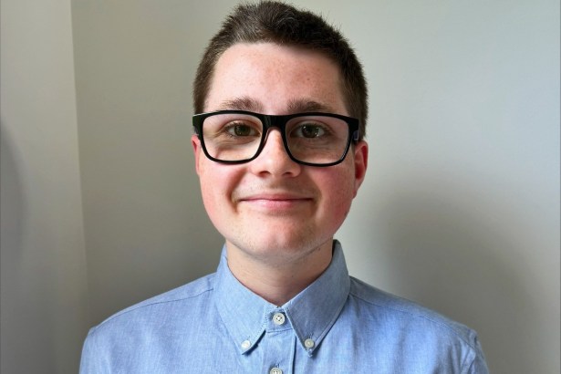 Mason Jones, a teenager in glasses and a blue shirt, smiling at the camera