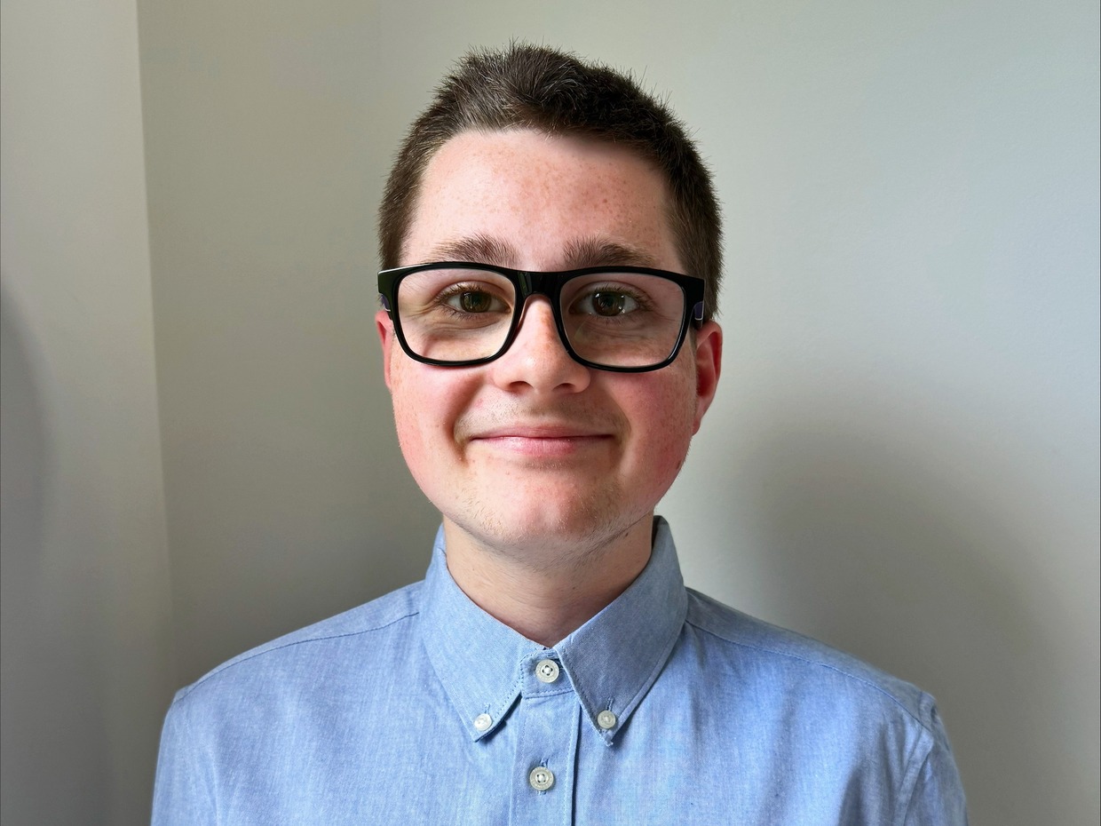 Mason Jones, a teenager in glasses and a blue shirt, smiling at the camera