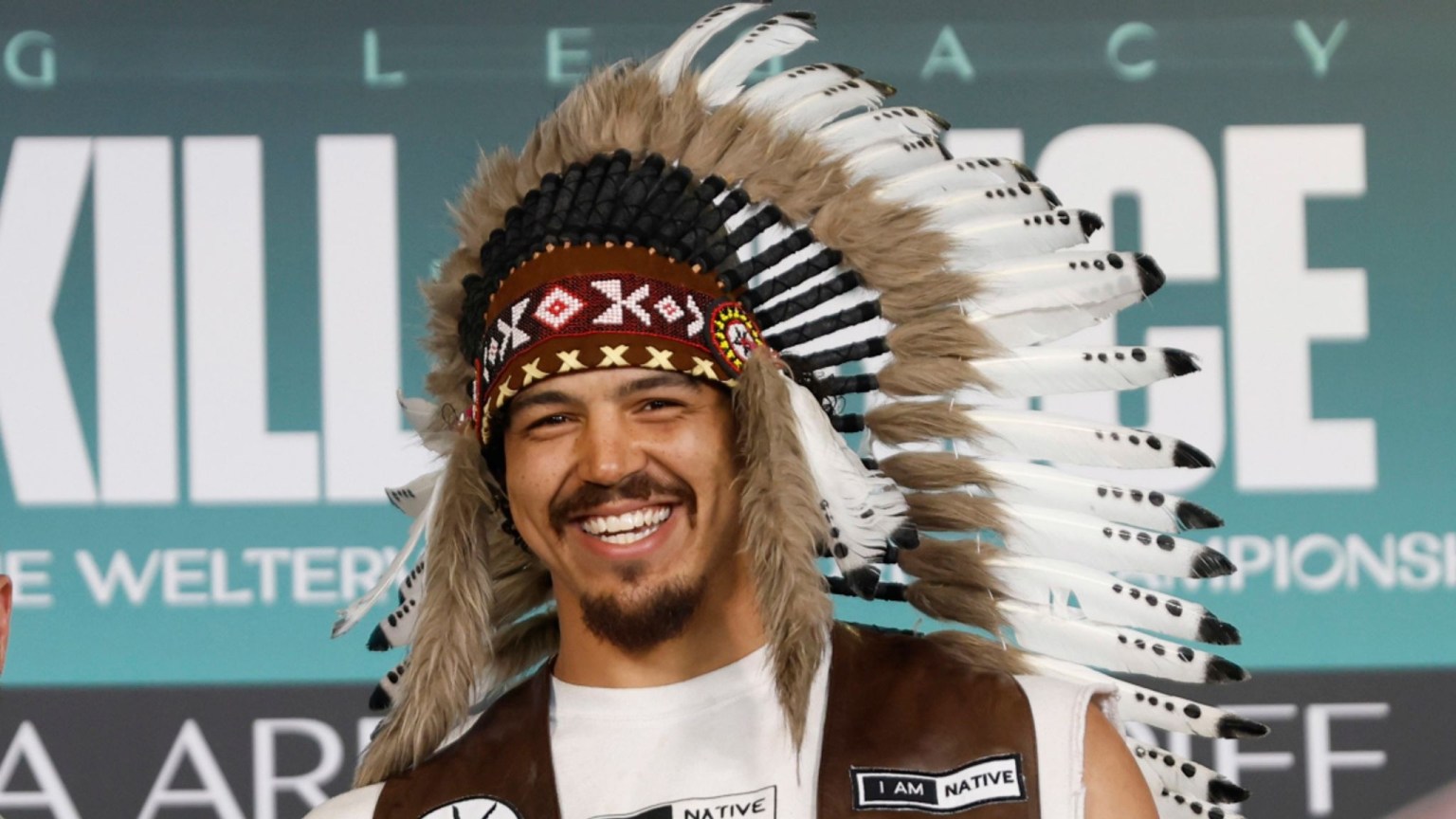 Swansea heavyweight Moses Jolly wearing a feathered headdress and an 'I am Native' waistcoat at a fight-week event