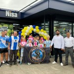 Sandfields Rangers players holding a banner and cheque hearts outside the new Nisa store in Port Talbot with the owners and balloons