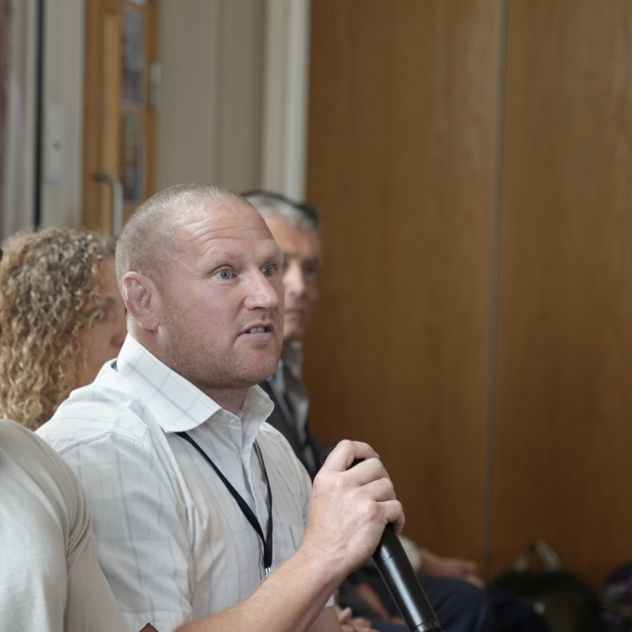 Gareth Richards speaking into a microphone at a community meeting