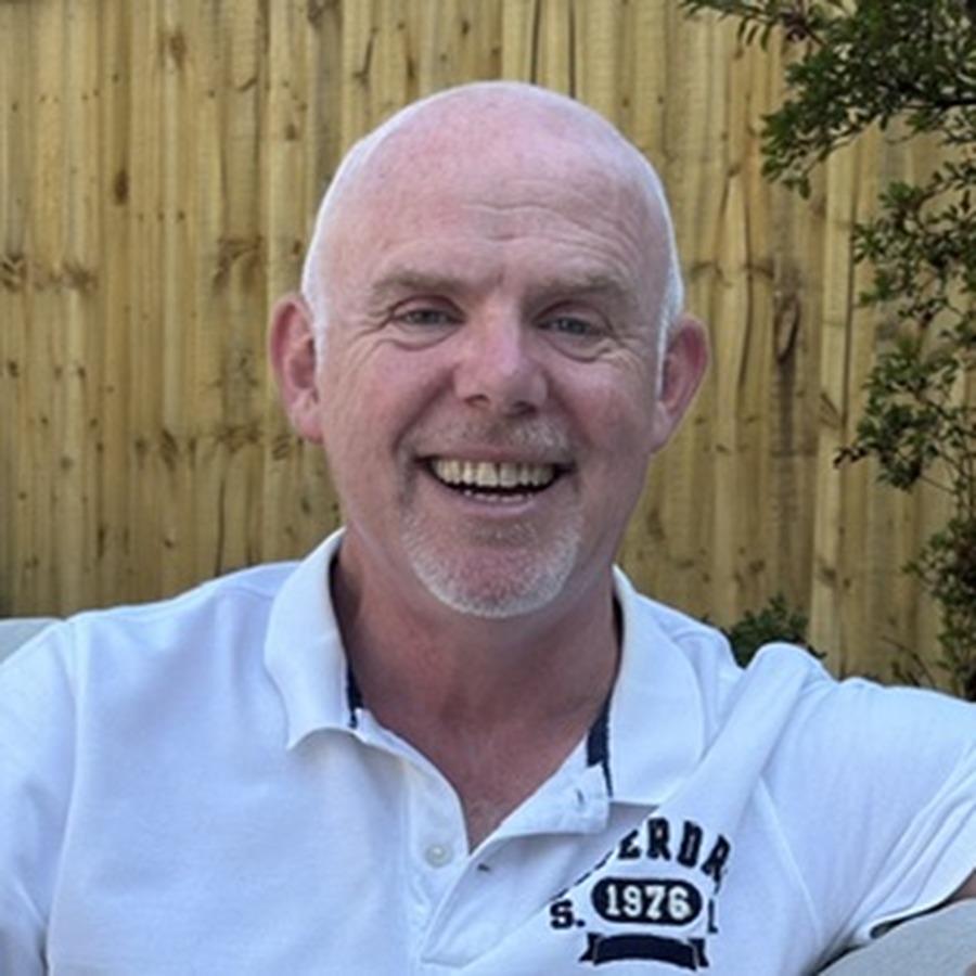 Timm Dadds, headteacher of Hafod Primary School, smiling in front of a wooden fence