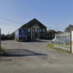 The entrance to Parsons Pickles at Burry Port, with a branded lorry parked outside the stone-fronted Ashburnham Works and palisade gates open onto the yard.
