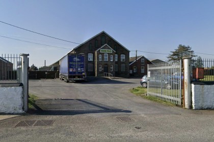 The entrance to Parsons Pickles at Burry Port, with a branded lorry parked outside the stone-fronted Ashburnham Works and palisade gates open onto the yard.