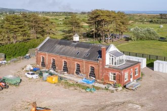 The Old Pump House at Pembrey seen from the air with a digger on cleared ground in front of it