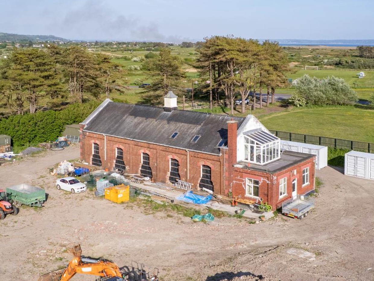 The Old Pump House at Pembrey seen from the air with a digger on cleared ground in front of it