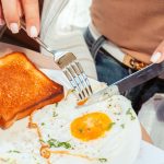 A cooked breakfast with two sunny side up fried eggs and toast on a plate