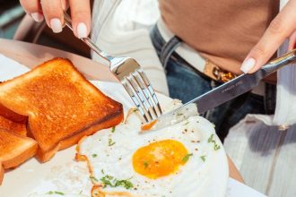 A cooked breakfast with two sunny side up fried eggs and toast on a plate