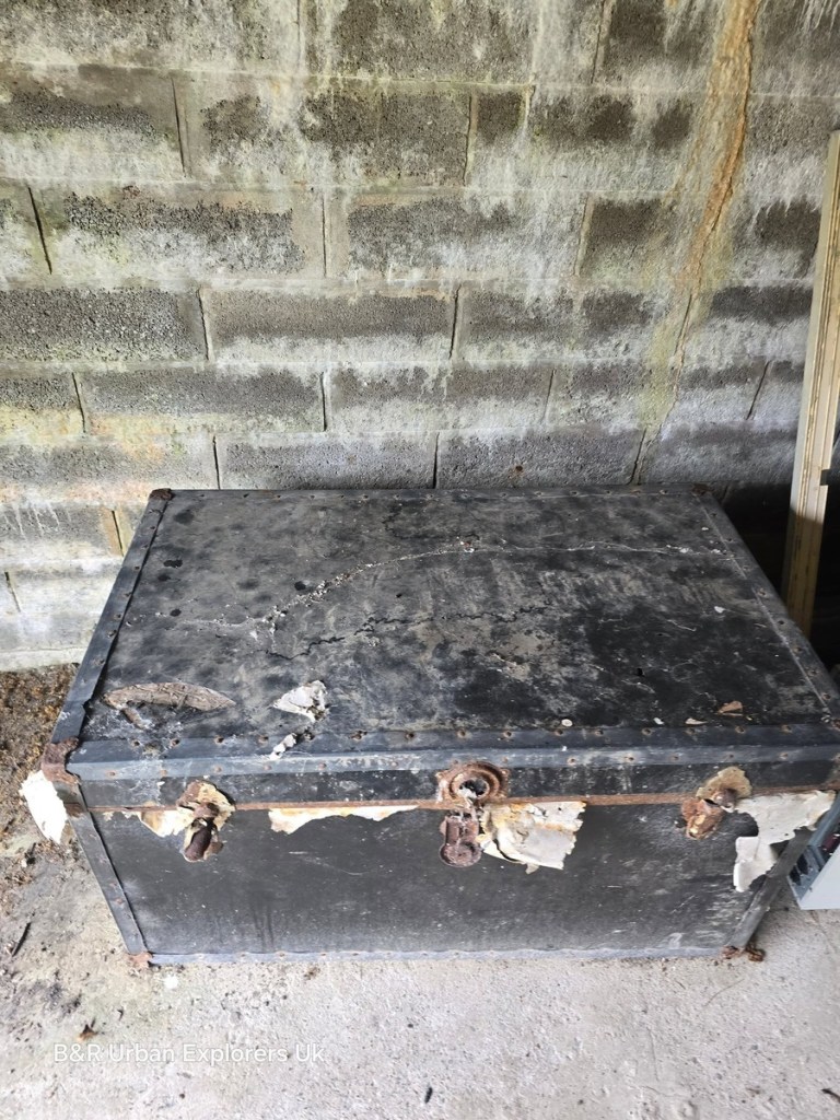 A rusted steel deed box on a bench inside a concrete basement vault at Rheola House