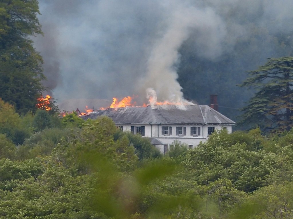 Fire and smoke starting to spread along one end of Rheola House's slate roof, most of the building still intact