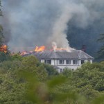 Fire and smoke starting to spread along one end of Rheola House's slate roof, most of the building still intact