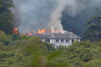 Fire and smoke starting to spread along one end of Rheola House's slate roof, most of the building still intact