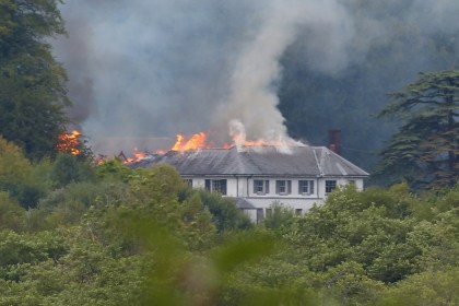 Fire and smoke starting to spread along one end of Rheola House's slate roof, most of the building still intact