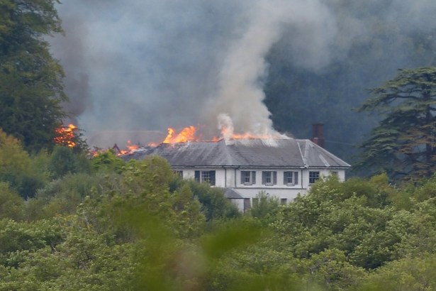 Fire and smoke starting to spread along one end of Rheola House's slate roof, most of the building still intact