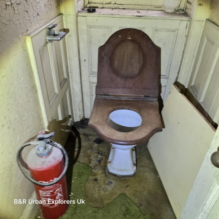 A Victorian mahogany-seated lavatory in a small tiled room at Rheola House with a fire extinguisher beside it