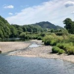 The River Towy running low with wide gravel banks exposed between the water and green riverbanks