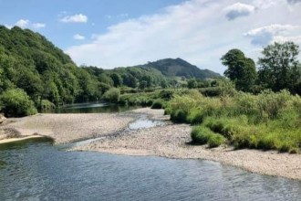 The River Towy running low with wide gravel banks exposed between the water and green riverbanks