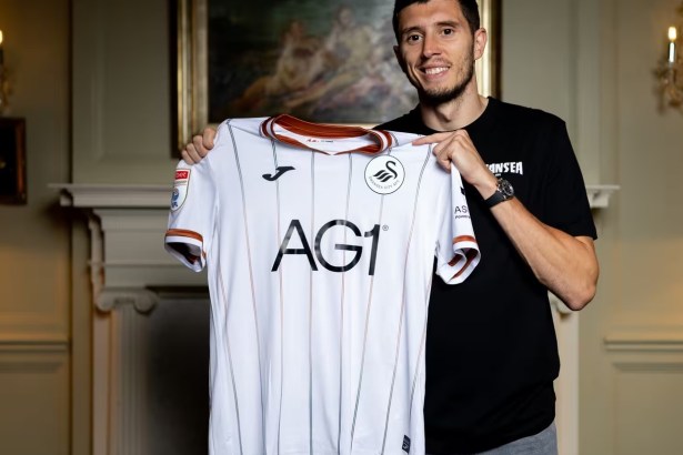 Ross Stewart holding up the white Swansea City shirt after signing for the club